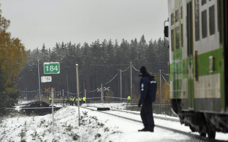 Rescue, military personnel and a policeman gather at the railroad crossing, where several people were killed in a crash between a train, right, and a military truck, left, by the track, in southern Finland Thursday Oct. 26, 2017.  Finnish media say several people have been killed in a train crash in the southern part of Finland. (Lehtikuva via AP)