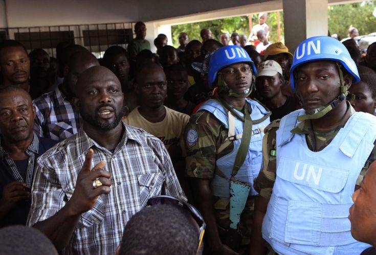 FILE-In this file photo taken on Wednesday, Nov. 9, 2011, opposition leader George Weah, left, is protected by United Nations peacekeepers from Nigeria as he speaks to supporters at opposition party headquarters in Monrovia, Liberia. President Ellen Johnson Sirleaf's son, who is running for a Senate seat, has filed a lawsuit contesting her Ebola-related ban on political rallies. Ahead of the Dec. 16, 2014,  election, the president banned gatherings in the capital, citing fears they could help spread Ebola. (AP Photo/Rebecca Blackwell, File)