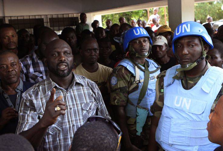 FILE-In this file photo taken on Wednesday, Nov. 9, 2011, opposition leader George Weah, left, is protected by United Nations peacekeepers from Nigeria as he speaks to supporters at opposition party headquarters in Monrovia, Liberia. President Ellen Johnson Sirleaf's son, who is running for a Senate seat, has filed a lawsuit contesting her Ebola-related ban on political rallies. Ahead of the Dec. 16, 2014, election, the president banned gatherings in the capital, citing fears they could help spread Ebola. (AP Photo/Rebecca Blackwell, File)