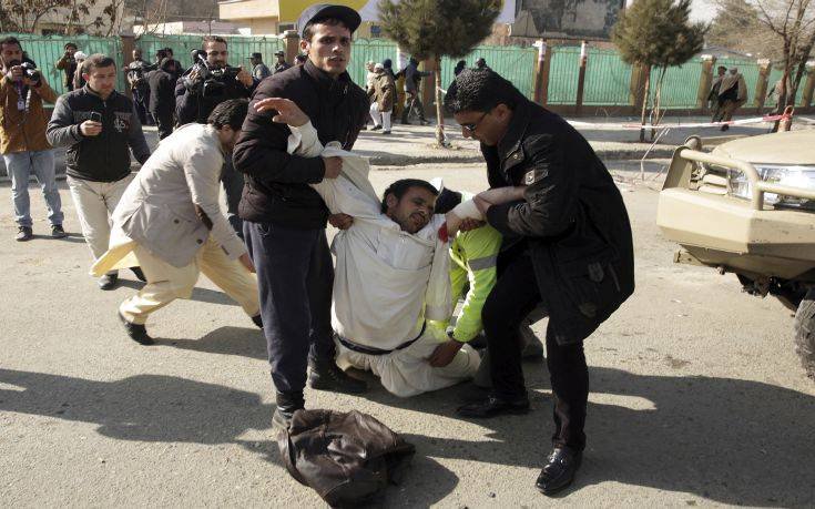 A wounded man is assisted at the site of a deadly suicide attack in the center of Kabul, Afghanistan, Saturday, Jan. 27, 2018. Afghan Public Health Ministry says dozens have been killed and over 100 wounded in suicide car bomb attack in capital Kabul. (AP Photo/Massoud Hossaini)