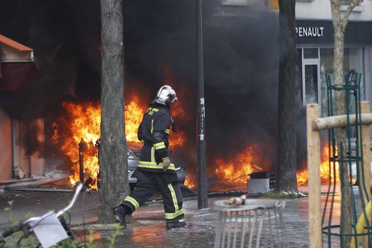 A firefighter walks past burning cars set on fire by activists during the traditional May Day rally in the center of Paris, France, Tuesday, May 1, 2018. Each year, people around the world take to the streets to mark International Workers' Day, or May Day. (AP Photo/Francois Mori)