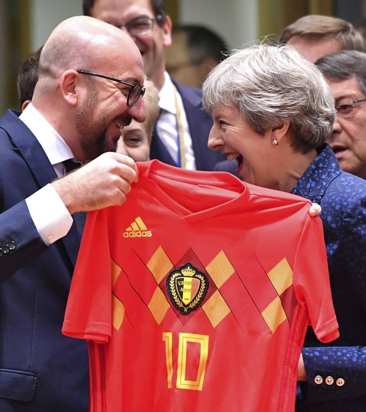 Belgian Prime Minister Charles Michel, left, presents a Belgian National Team jersey to British Prime Minister Theresa May during a round table meeting at an EU summit in Brussels, Thursday, June 28, 2018. European Union leaders meet for a two-day summit to address the political crisis over migration and discuss how to proceed on the Brexit negotiations. (AP Photo/Geert Vanden Wijngaert)