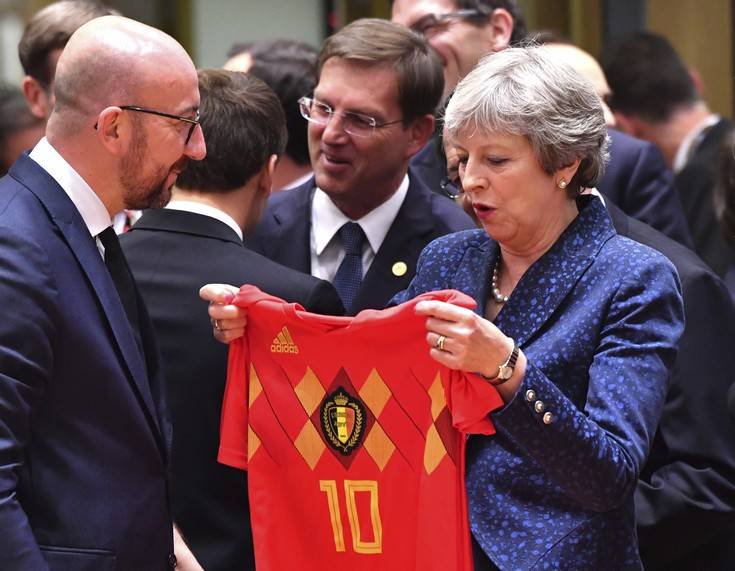 Belgian Prime Minister Charles Michel, left, presents a Belgian National Team jersey to British Prime Minister Theresa May during a round table meeting at an EU summit in Brussels, Thursday, June 28, 2018. European Union leaders meet for a two-day summit to address the political crisis over migration and discuss how to proceed on the Brexit negotiations. (AP Photo/Geert Vanden Wijngaert)