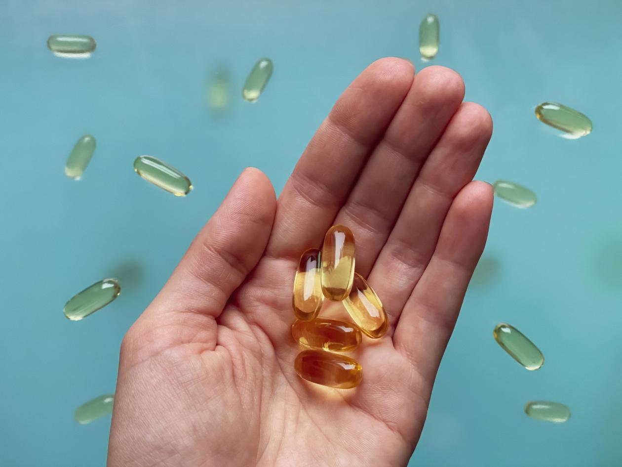 In The Hand Several Omega 3 Capsules Against The Background Of Omega 3 Capsules Levitating In The Ai
