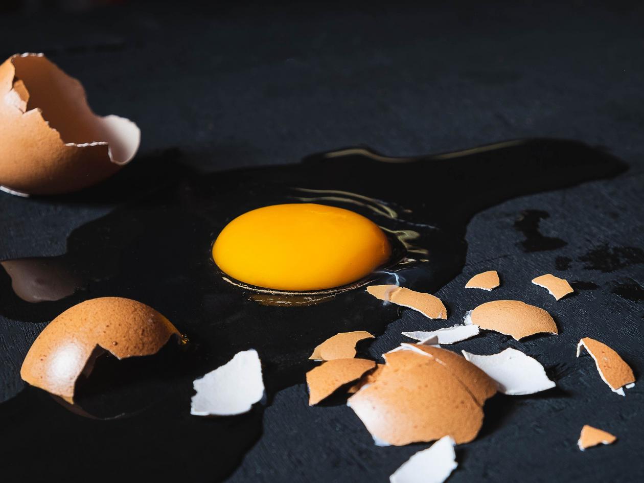 A Cracked Egg With An Egg Shell, Egg Yolk And Egg White On White Background