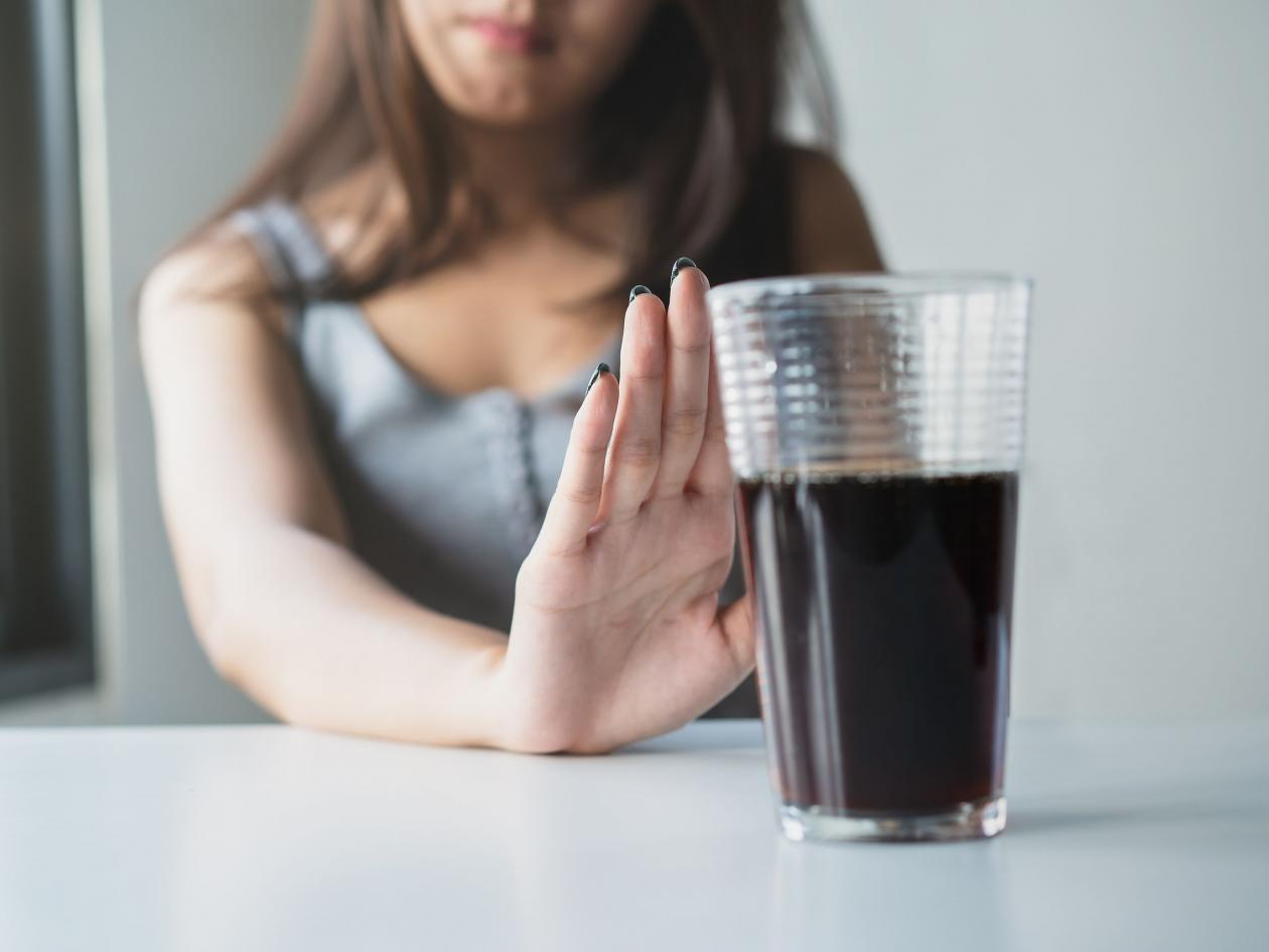 Limits Sugar Diet In Food Concepts. Young Woman Showing Bad Hand Symbol To Soft Drink Soda That Have