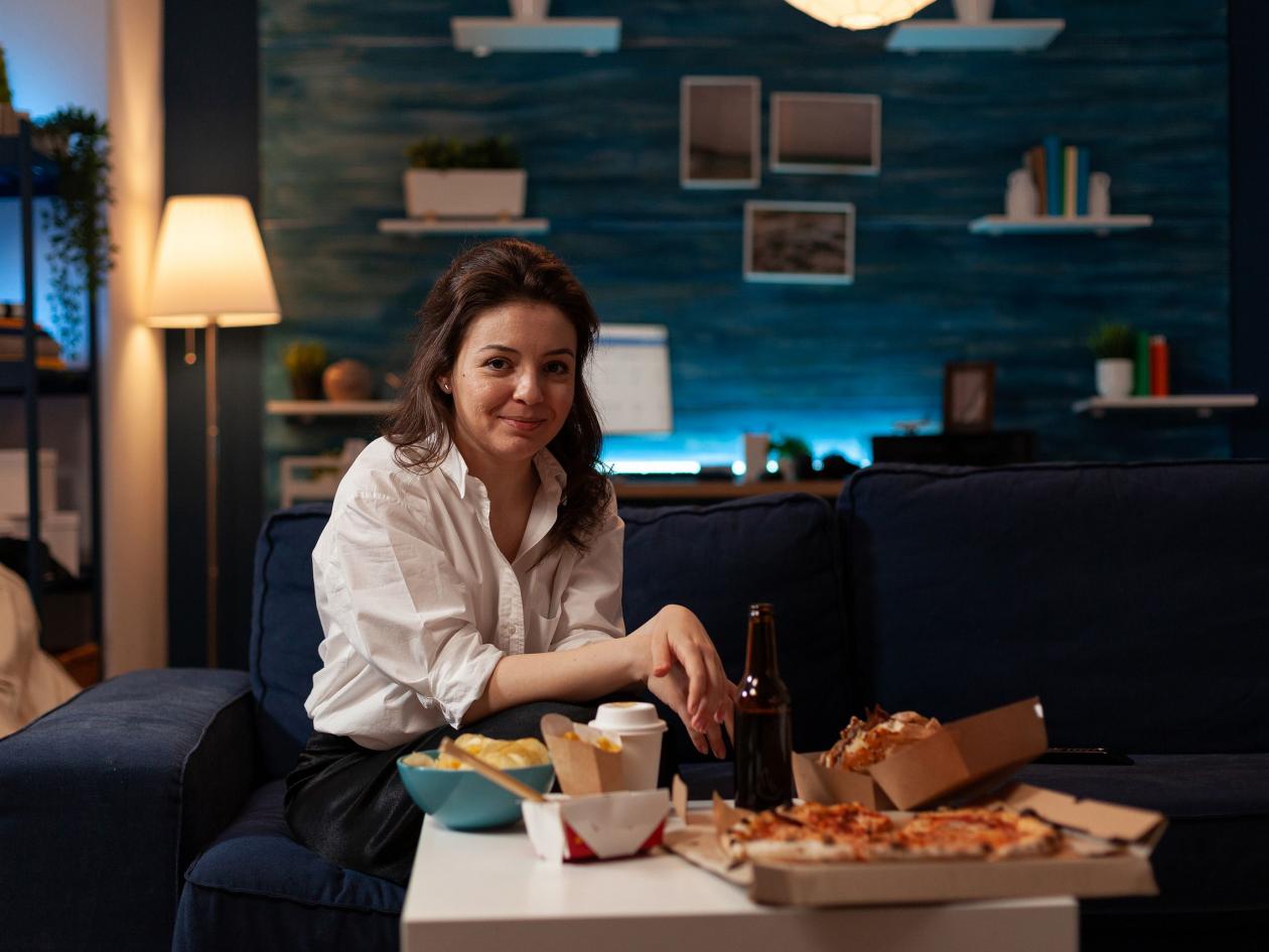 Portrait Of Smiling Woman Relaxing On Couch After Office Work Enjoying Fast Food Dinner In The Eveni